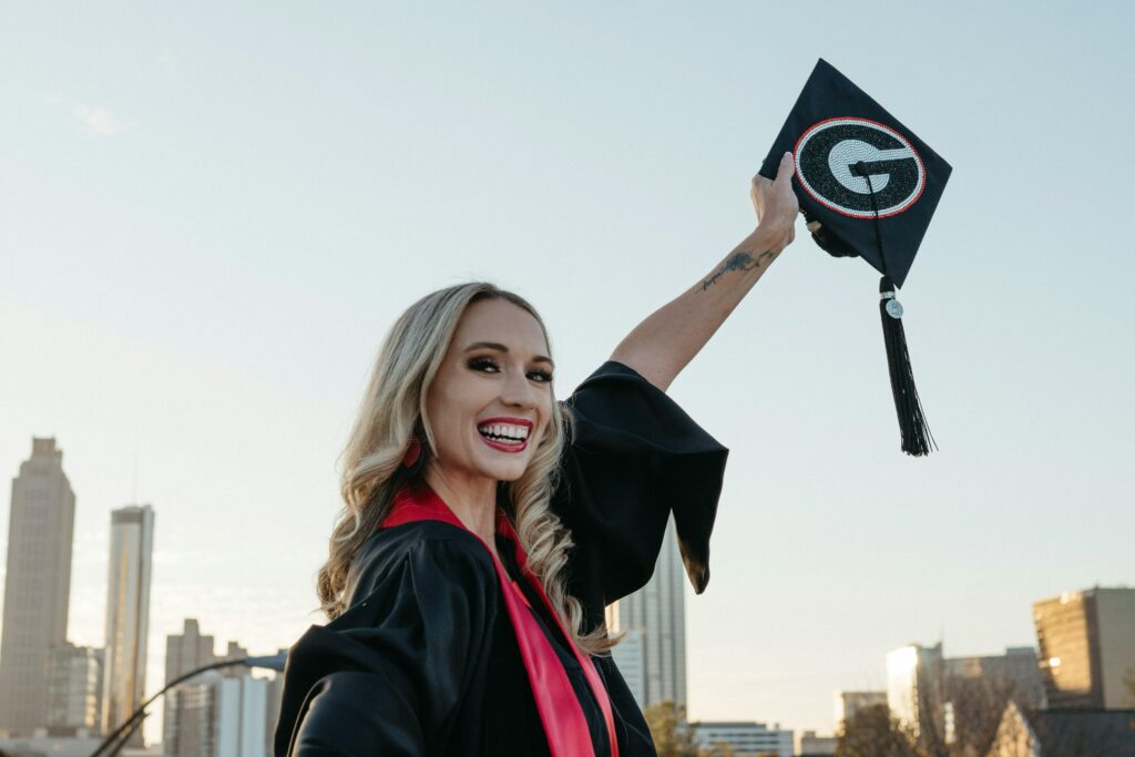 Joyful female graduate celebrating with cap in Atlanta skyline background.
